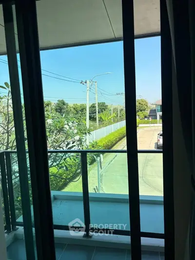 Charming balcony view with lush greenery and clear blue sky, perfect for relaxation and outdoor enjoyment.
