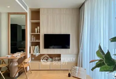 Modern living room with stylish decor and large TV, featuring natural light and elegant furnishings.