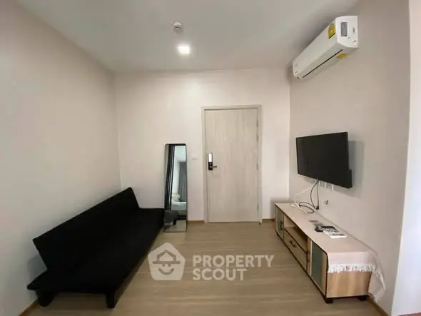 Modern living room with sleek furniture and wall-mounted TV in a cozy apartment.