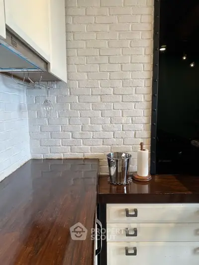 Stylish kitchen with white brick wall and dark wooden countertop, featuring modern decor elements.