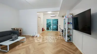 Spacious living room with modern decor and large TV, featuring herringbone flooring.