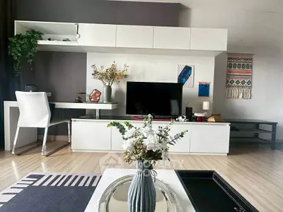 Modern living room with stylish decor and sleek furniture, featuring a TV and elegant shelving.