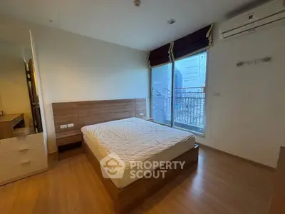 Modern bedroom with wooden flooring and large window in a stylish apartment.
