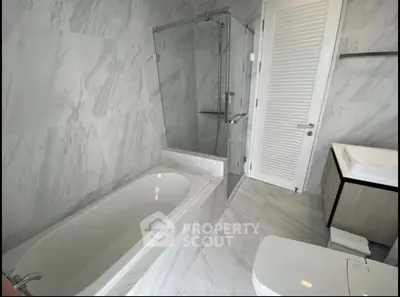 Luxurious modern bathroom with marble tiles and glass shower enclosure