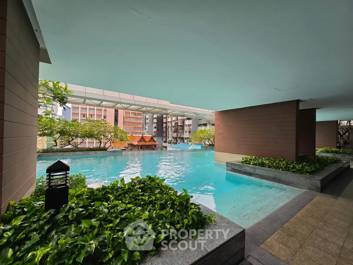 Luxurious condominium pool area with lush greenery and modern architecture, perfect for relaxation and leisure.