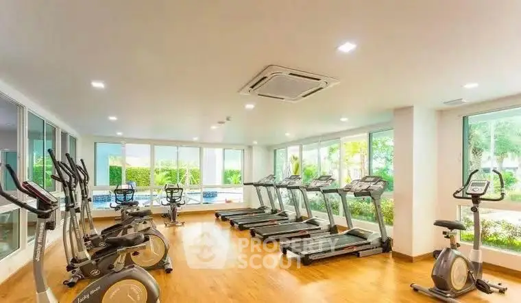 Spacious gym with modern equipment and large windows offering garden views.