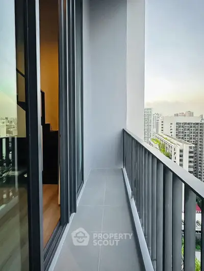 Modern high-rise apartment balcony with city view and sleek railing design.