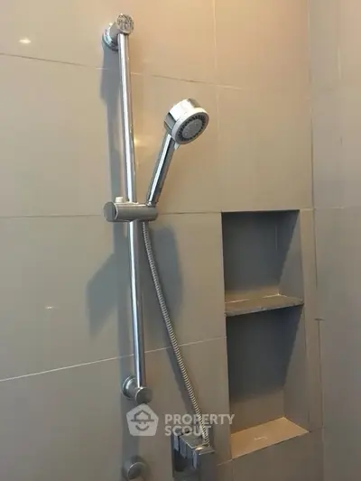 Modern bathroom shower with sleek chrome fixtures and built-in shelving.