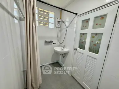 Compact bathroom with shower, sink, and floral door design