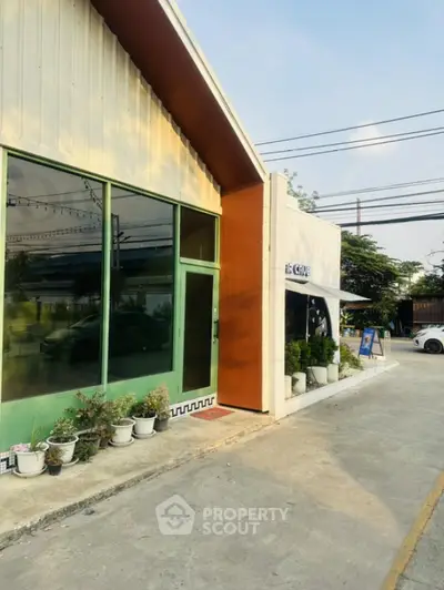 Modern commercial building exterior with large glass windows and potted plants