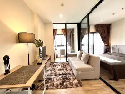 Modern living room with cozy sofa, stylish decor, and glass partition leading to bedroom in a chic apartment.