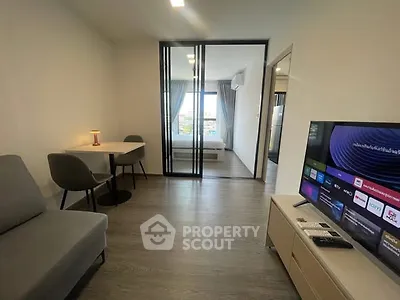 Modern living room with sleek design and smart TV, adjacent to a cozy bedroom with city view.