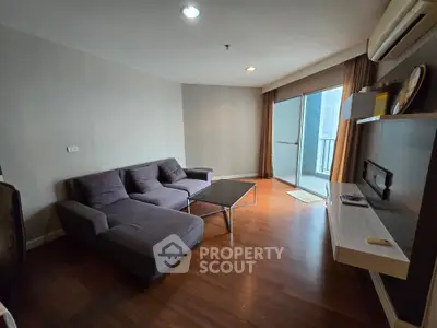 Modern living room with sleek furniture and balcony access, featuring hardwood floors and ample natural light.