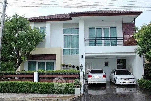 Modern two-story house with large windows and two cars parked in the driveway.