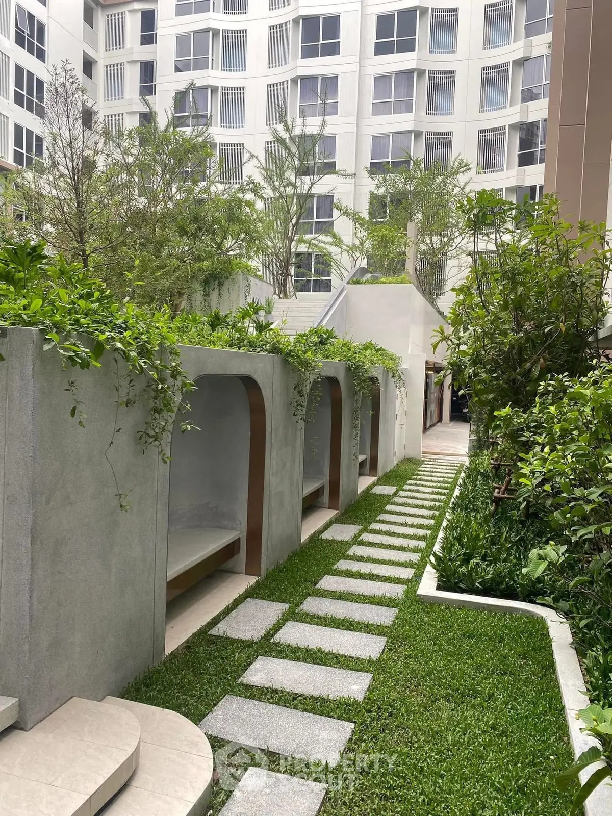 Luxurious garden area with modern architecture and lush greenery in a high-rise residential complex.
