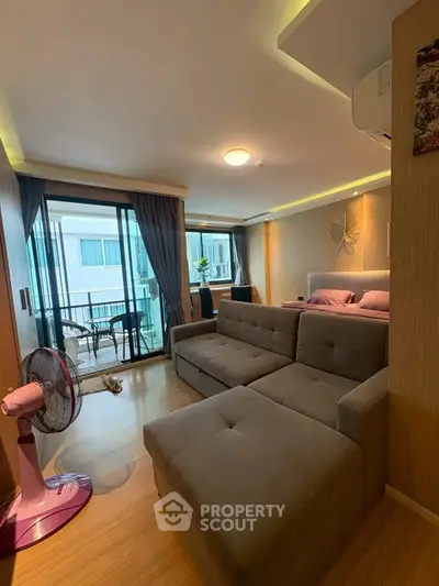 Modern living room with balcony access, featuring stylish furniture and natural light.