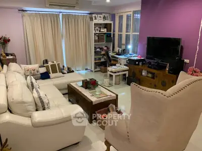 Cozy living room with white leather sofas, purple accent wall, and entertainment center.