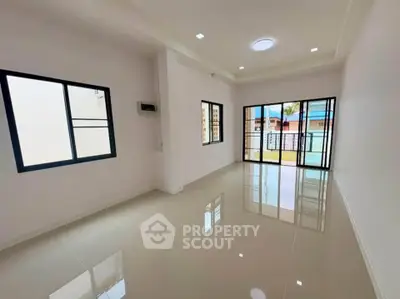 Spacious modern living room with large windows and glossy tiled floors.