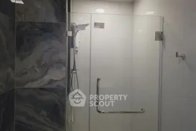 Modern bathroom with sleek glass shower enclosure and stylish tile design.