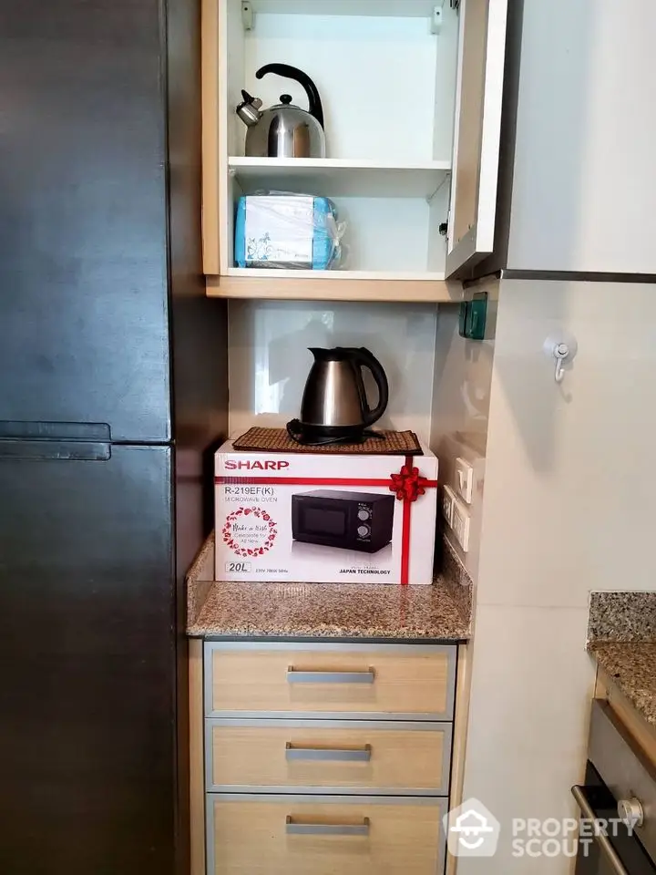 Modern kitchen corner with microwave and kettle on granite countertop