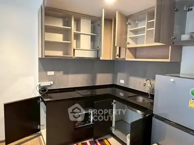Modern kitchen with sleek black countertops and ample cabinet space in a stylish apartment.