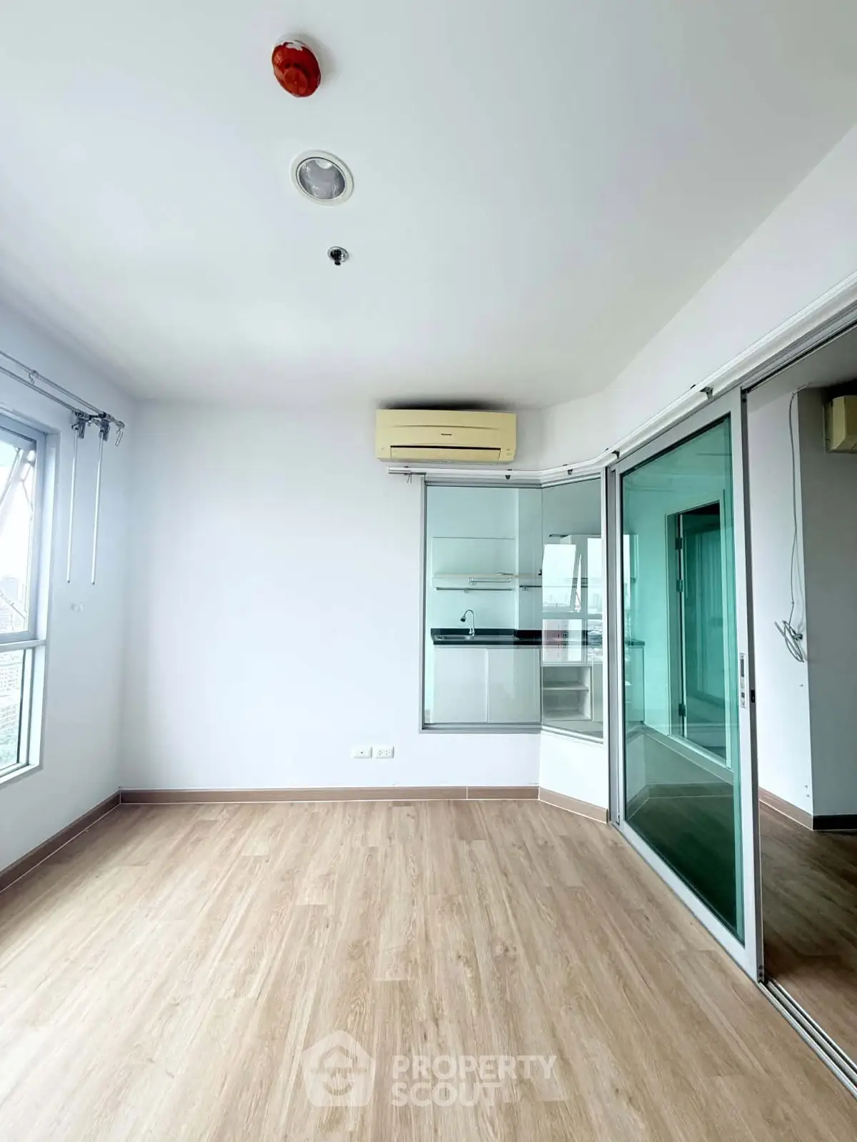 Spacious unfurnished room with wooden flooring and large windows in modern apartment.