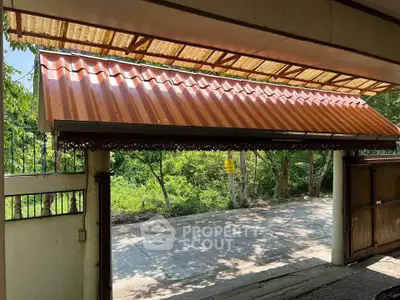 Charming gated entrance with red-tiled roof and lush greenery view, perfect for privacy and tranquility.
