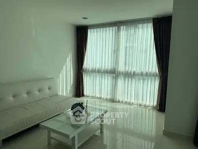 Bright modern living room with white sofa and large window, perfect for relaxation.