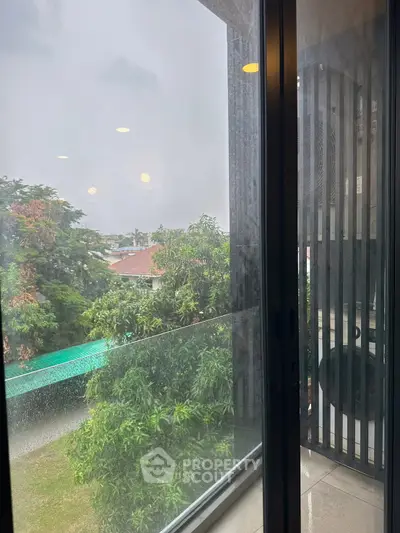 Modern balcony with glass railing offering lush green views and ample natural light.