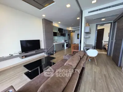 Modern open-plan living room with sleek furniture and wooden flooring in a stylish apartment.