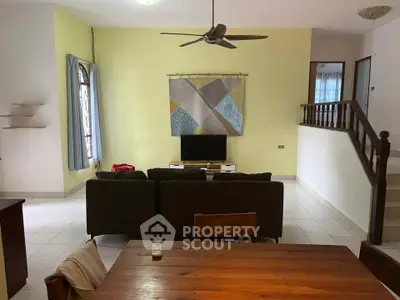Spacious living room with modern decor and ceiling fan, ideal for family gatherings.