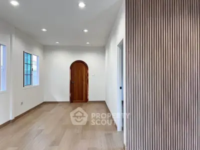 Spacious modern interior with wooden flooring and unique arched door, perfect for stylish living.