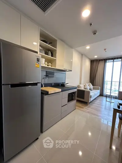 Modern open-layout kitchen with sleek appliances and cozy living area in a stylish apartment.