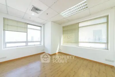 Spacious empty room with large windows and wooden flooring in modern building