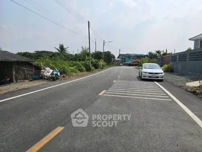 Scenic suburban road with parked car and lush greenery, ideal for peaceful living.
