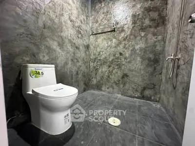 Modern industrial-style bathroom with concrete walls and sleek fixtures.