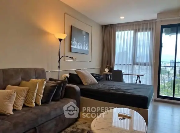 Modern studio apartment with cozy living area and large windows offering city views.