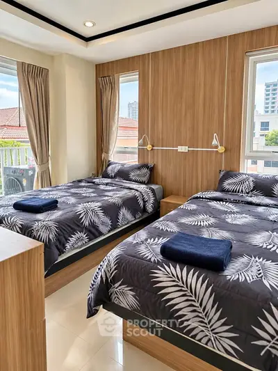 Modern bedroom with twin beds and large windows offering city views
