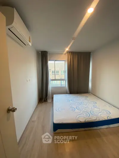 Cozy bedroom with large window and air conditioning, perfect for relaxation.