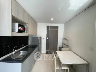 Modern kitchen with sleek cabinetry, stainless steel appliances, and dining area in a compact layout.