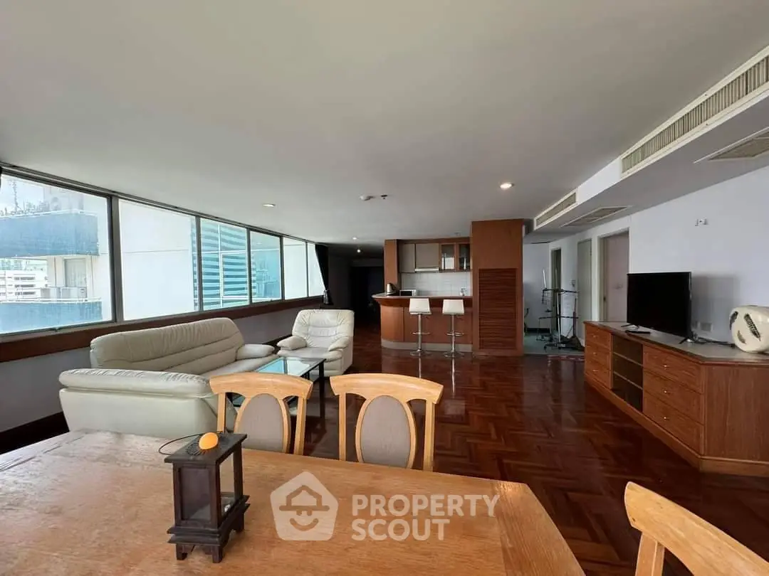 Spacious living room with modern furniture and large windows offering city views.