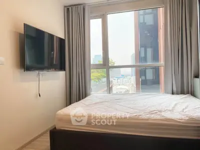 Modern bedroom with large window and wall-mounted TV in urban apartment