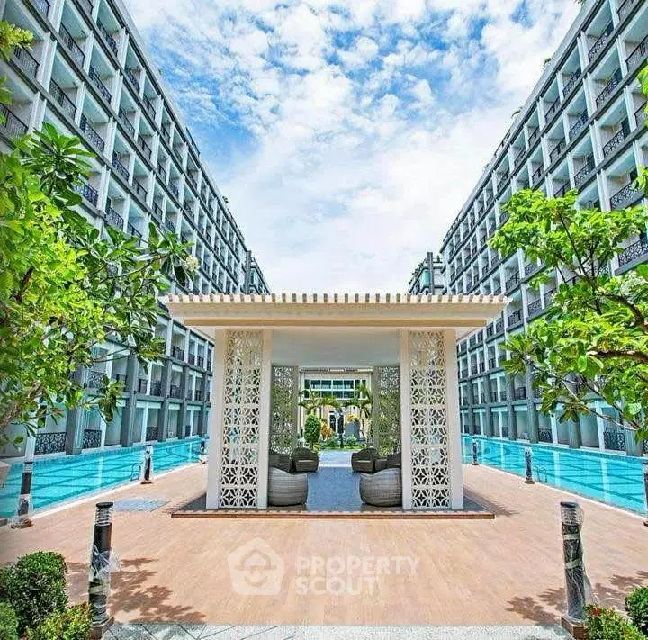 Luxurious modern apartment complex with stunning poolside view and lush greenery.