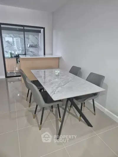 Modern dining area with sleek marble table and stylish chairs in open kitchen layout.