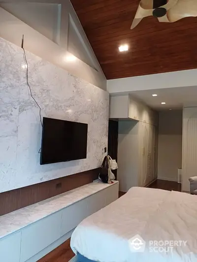 Luxurious bedroom with modern TV setup and stylish ceiling design