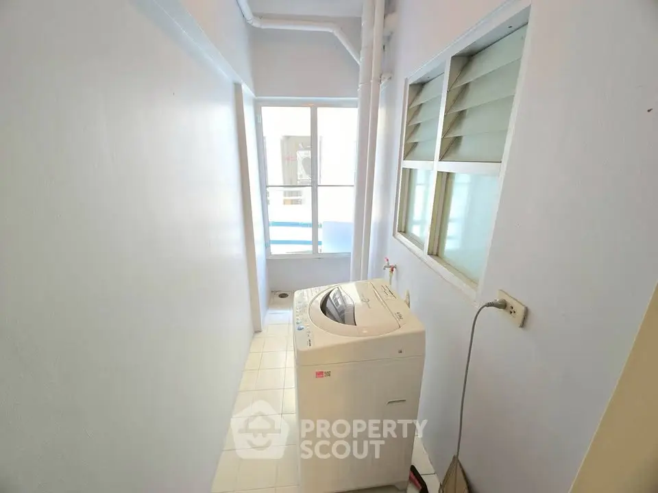 Compact laundry area with washing machine and bright window view