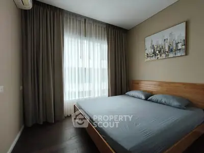 Modern bedroom with wooden bed frame and cityscape artwork, featuring floor-to-ceiling windows and elegant curtains.
