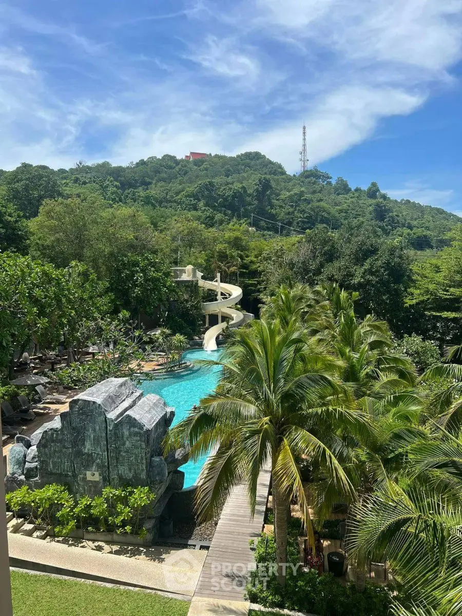 Luxurious resort pool with waterslide and lush greenery, perfect for relaxation and leisure.