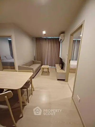 Modern living room with dining area in a cozy apartment, featuring neutral tones and minimalist furniture.