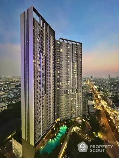 Stunning high-rise building with illuminated pool and panoramic city view at dusk.